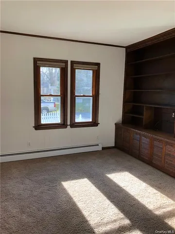 a view of an empty room with furniture and window