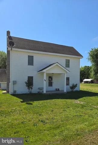 a front view of house with yard and trees in the background