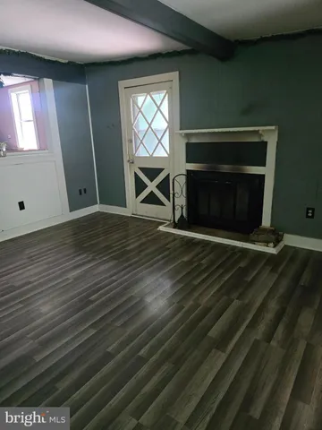 a view of empty room with wooden floor and fireplace
