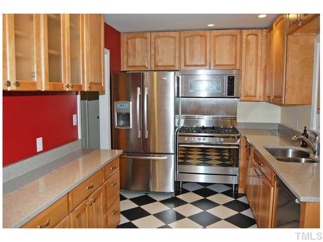 3317 Octavia Street Raleigh, NC 27606 - Photo 6 of 25 Cooking is a delight in the updated kitchen that offers stainless steel appliances, granite counters, large cabinets, checker tile floors, and a glass French door to the screened porch.