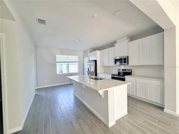 a kitchen with stainless steel appliances a sink a stove a refrigerator cabinets and a window