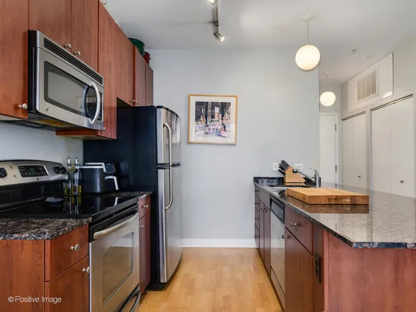 a kitchen with stainless steel appliances granite countertop a stove top oven a sink dishwasher and a microwave with wooden cabinets