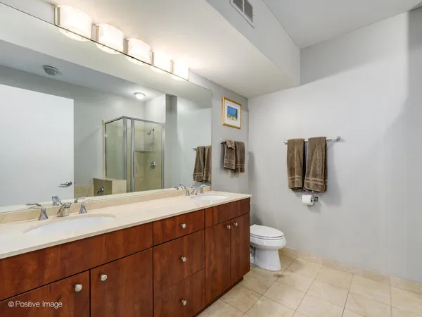 a spacious bathroom with a double vanity sink toilet and mirror