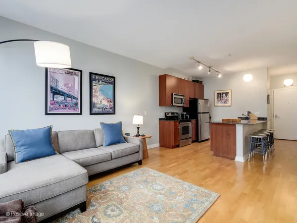 a living room with furniture kitchen view and a wooden floor