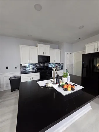 a kitchen with stainless steel appliances kitchen island granite countertop a refrigerator a stove a sink and white cabinets