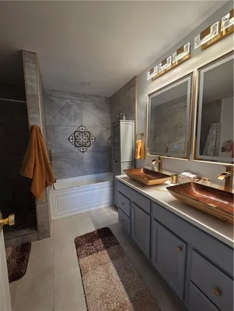 a bathroom with a sink a large mirror and a bathtub