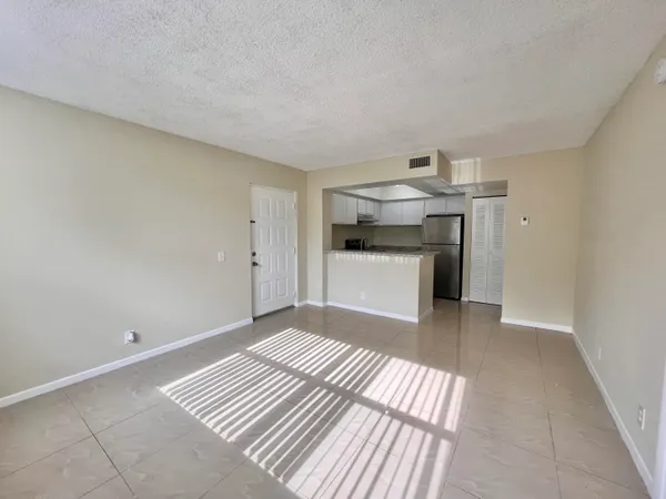a view of kitchen and empty room with wooden floor
