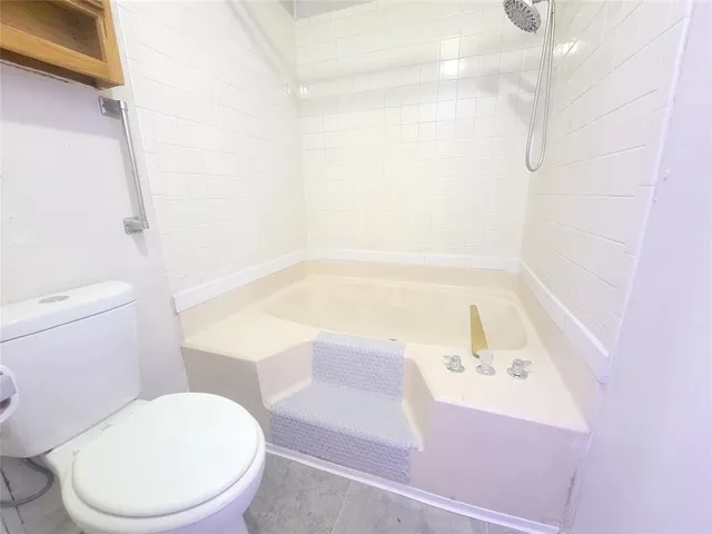 a white toilet sitting next to a bath tub