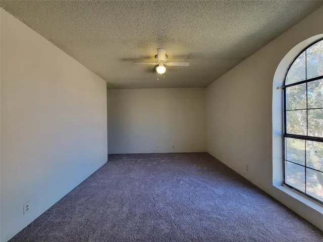 an empty room with windows and ceiling fan