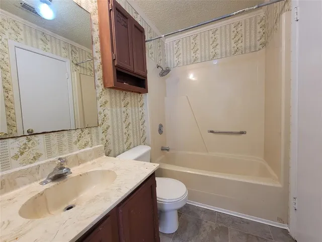 a bathroom with a granite countertop sink a toilet and shower