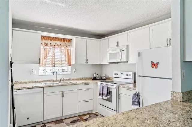 a kitchen with white cabinets sink and white appliances