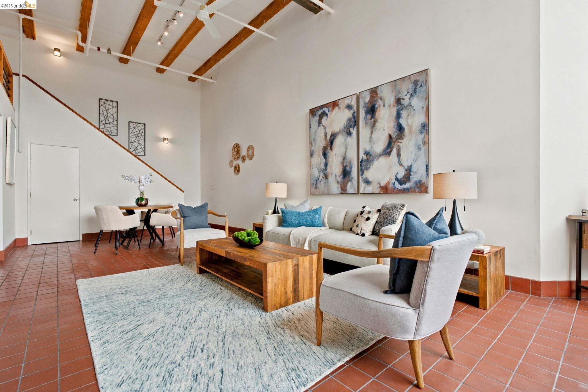 1920 Union Street, Unit 9 Oakland, CA 94607 - Photo 5 of 35 Spacious living area featuring exposed beam ceilings, terracotta tile flooring, a dining alcove, and an open-tread staircase