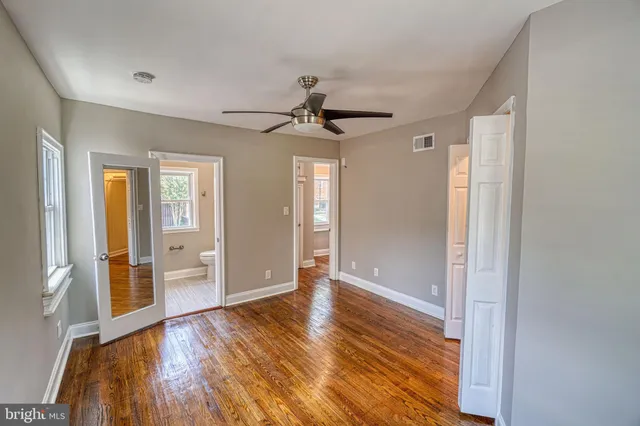 a view of empty room with wooden floor and fan