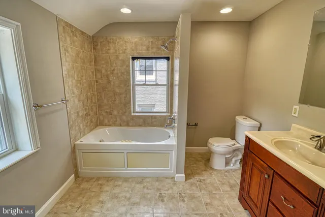 a bathroom with a tub a sink and a large mirror