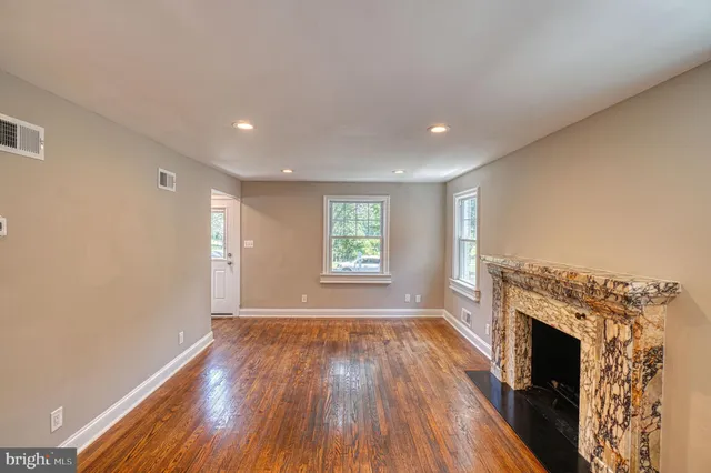 an empty room with wooden floor fireplace and windows