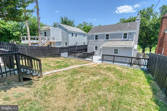 a view of a backyard with wooden fence and large trees
