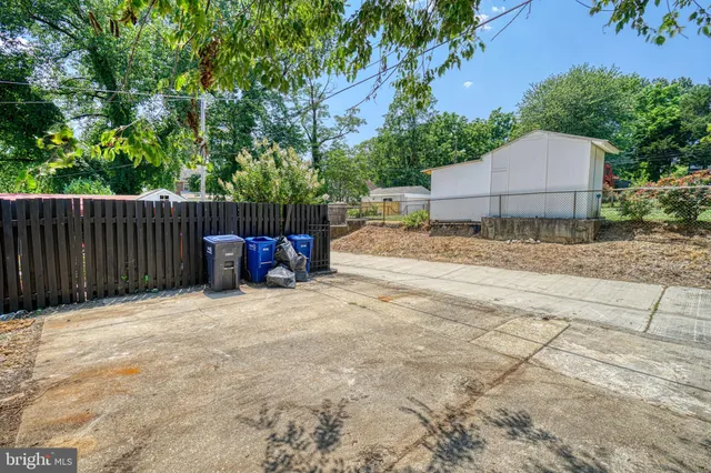 a backyard of a house with table and chairs and wooden fence