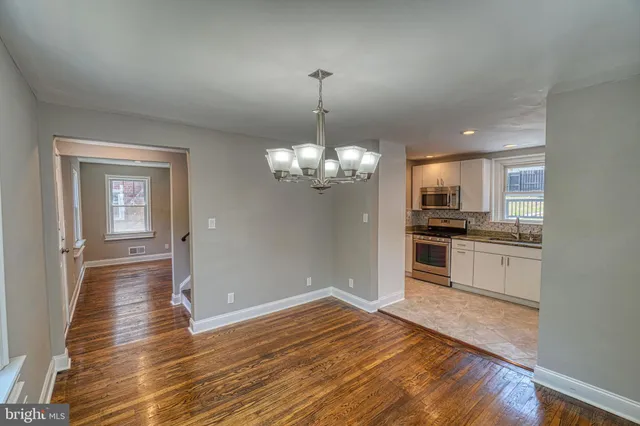 an empty room with wooden floor chandelier and windows