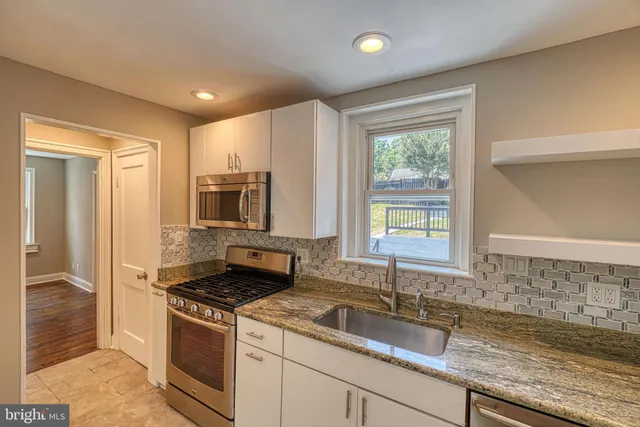 an empty room with wooden floor closet and windows