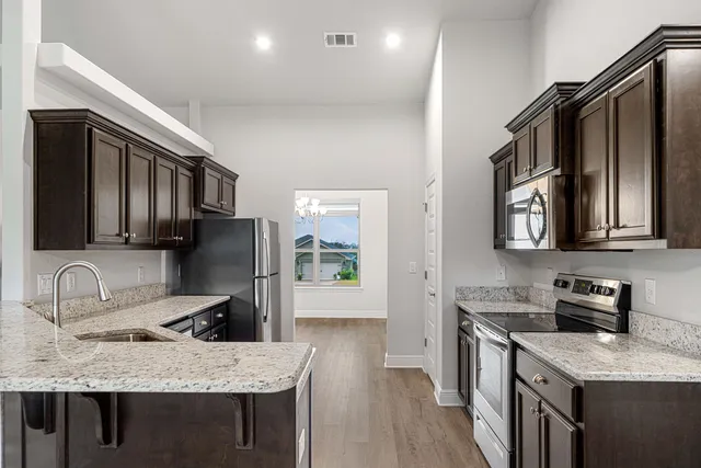 a kitchen with stainless steel appliances granite countertop a sink stove and refrigerator