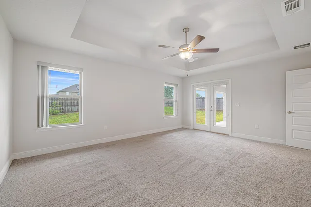 an empty room with windows and ceiling fan