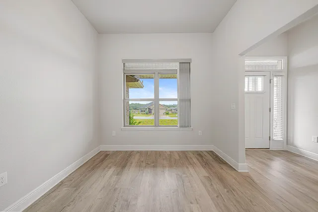 an empty room with a window and wooden floor