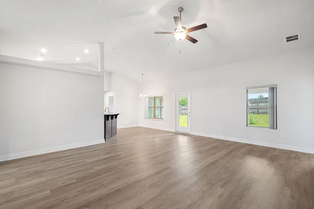 a view of an empty room with a window and wooden floor