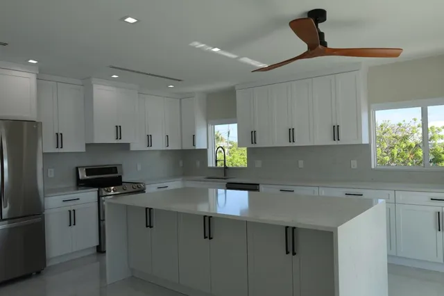 a kitchen with stainless steel appliances a sink a stove a refrigerator and cabinets