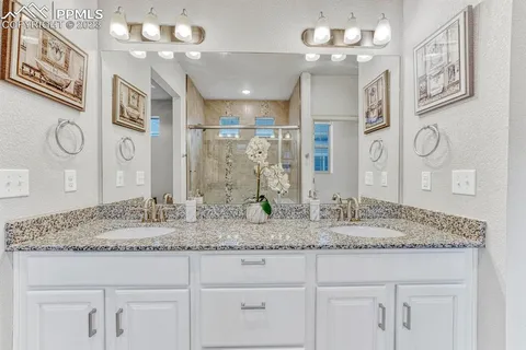 a bathroom with a granite countertop double vanity sink and a mirror