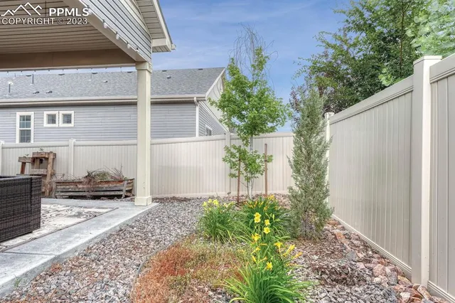 a backyard of a house with plants and barbeque oven