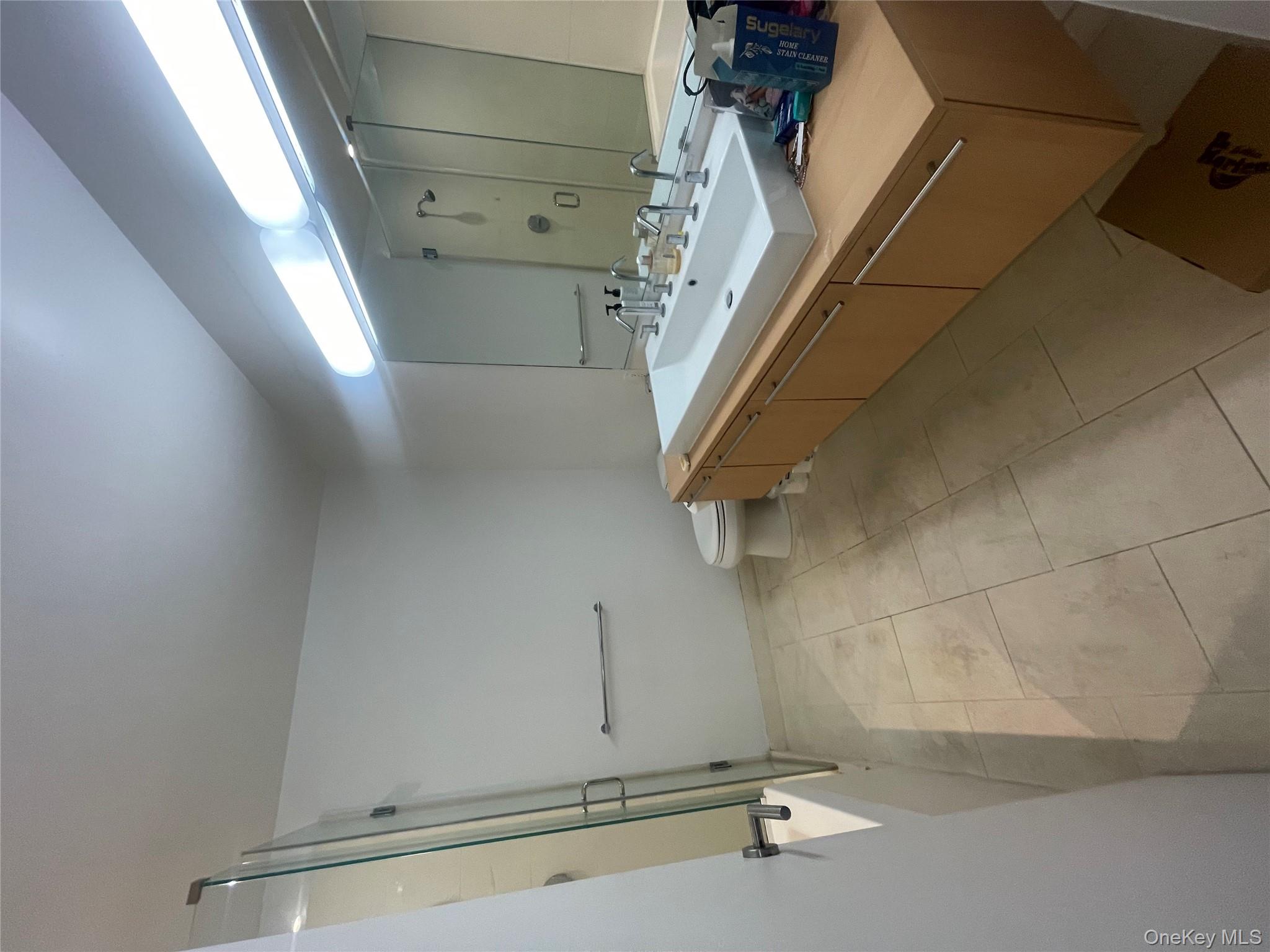 119 Fulton Street, Unit 5B Manhattan, NY 10038 - Photo 12 of 15 Full bathroom with a shower with door, vanity, and tile patterned flooring