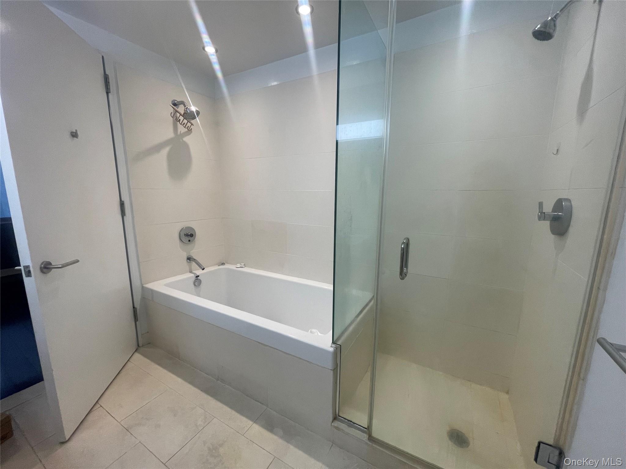 119 Fulton Street, Unit 5B Manhattan, NY 10038 - Photo 13 of 15 Full bath with tiled shower, tile patterned floors, and a tub to relax in