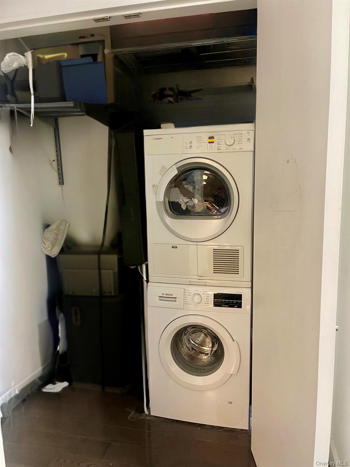 119 Fulton Street, Unit 5B Manhattan, NY 10038 - Photo 5 of 15 Clothes washing area featuring baseboards and stacked washing maching and dryer