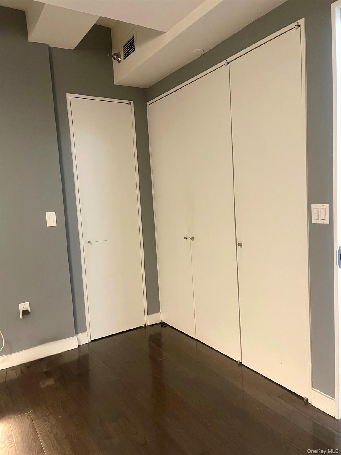 119 Fulton Street, Unit 5B Manhattan, NY 10038 - Photo 9 of 15 Unfurnished bedroom featuring a closet and dark wood-style flooring