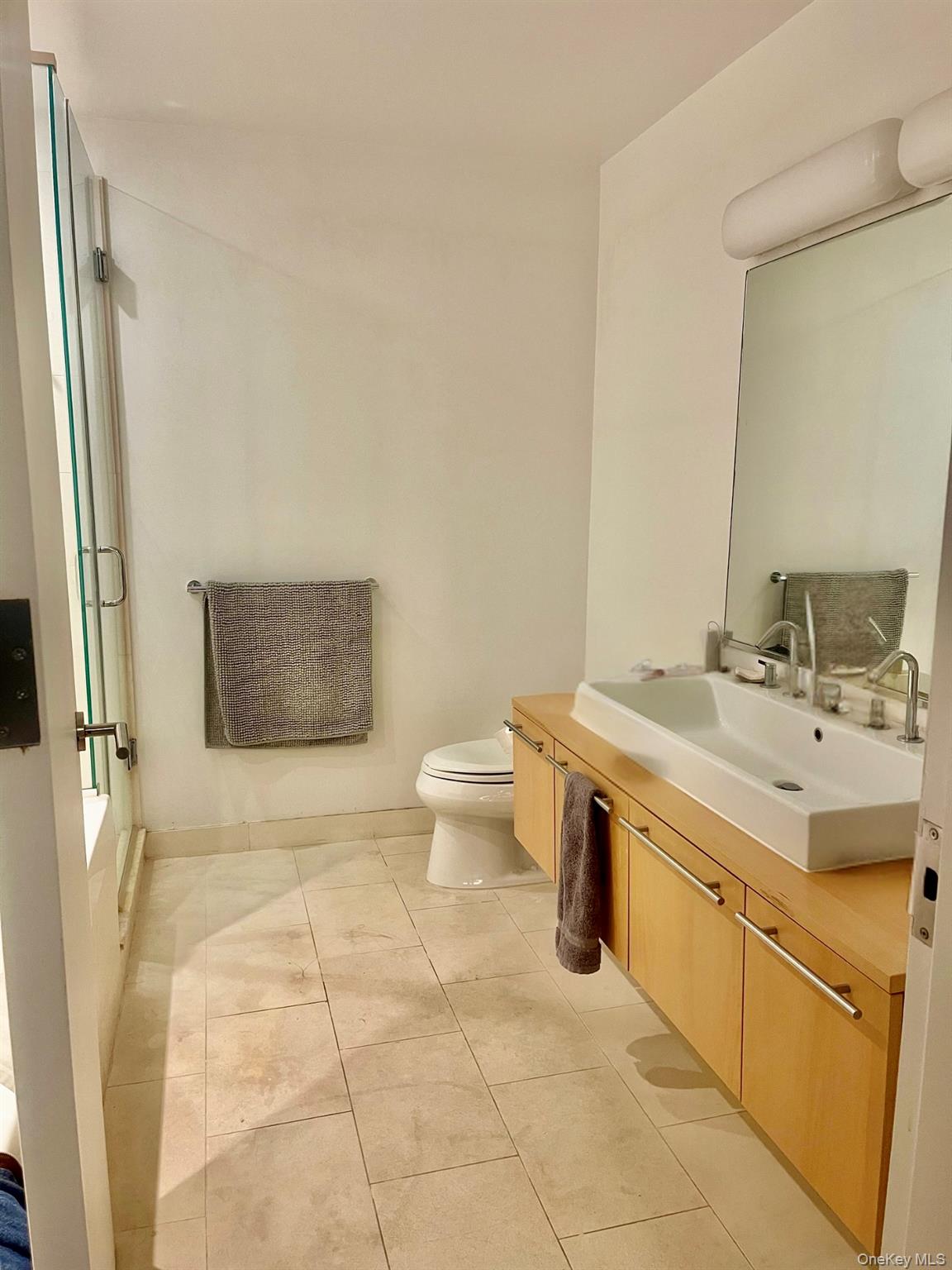 119 Fulton Street, Unit 5B Manhattan, NY 10038 - Photo 10 of 15 Full bath with bath / shower combo with glass door, vanity, and toilet