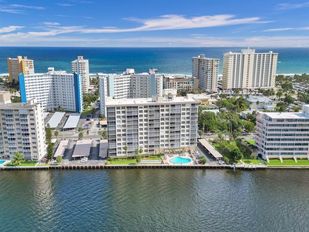 299 North Riverside Drive, Unit 303 Pompano Beach, FL 33062 - Photo 1 of 40 a front view of a residential apartment building with a yard and outdoor seating