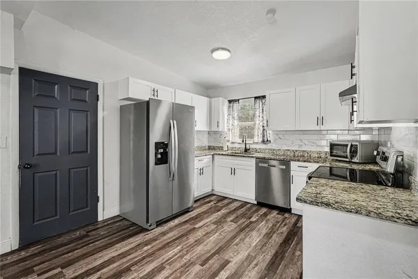a kitchen with granite countertop a refrigerator and a sink