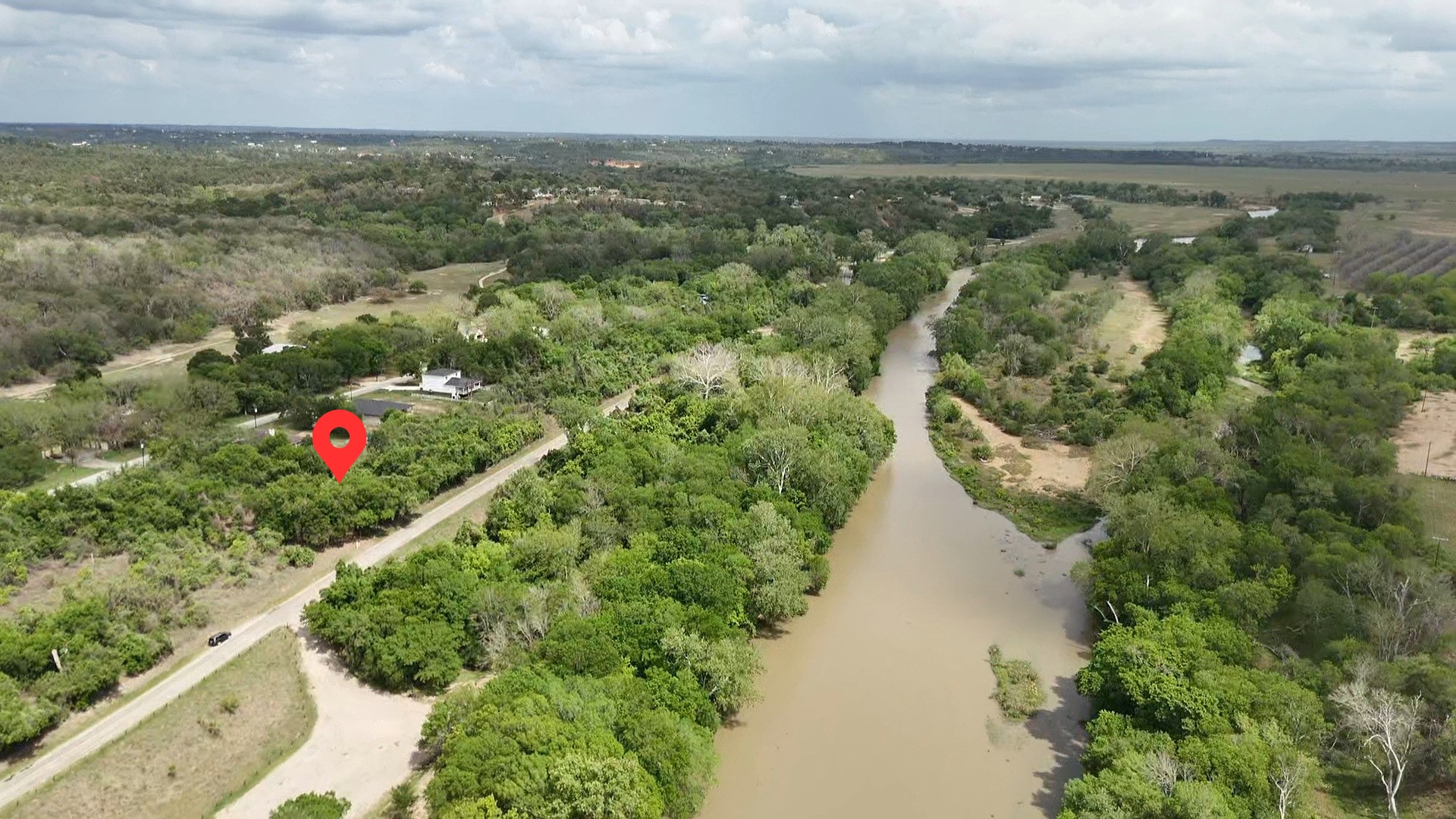 Aerial view highlighting the property's location amidst lush green trees, with a visible river in the surrounding landscape