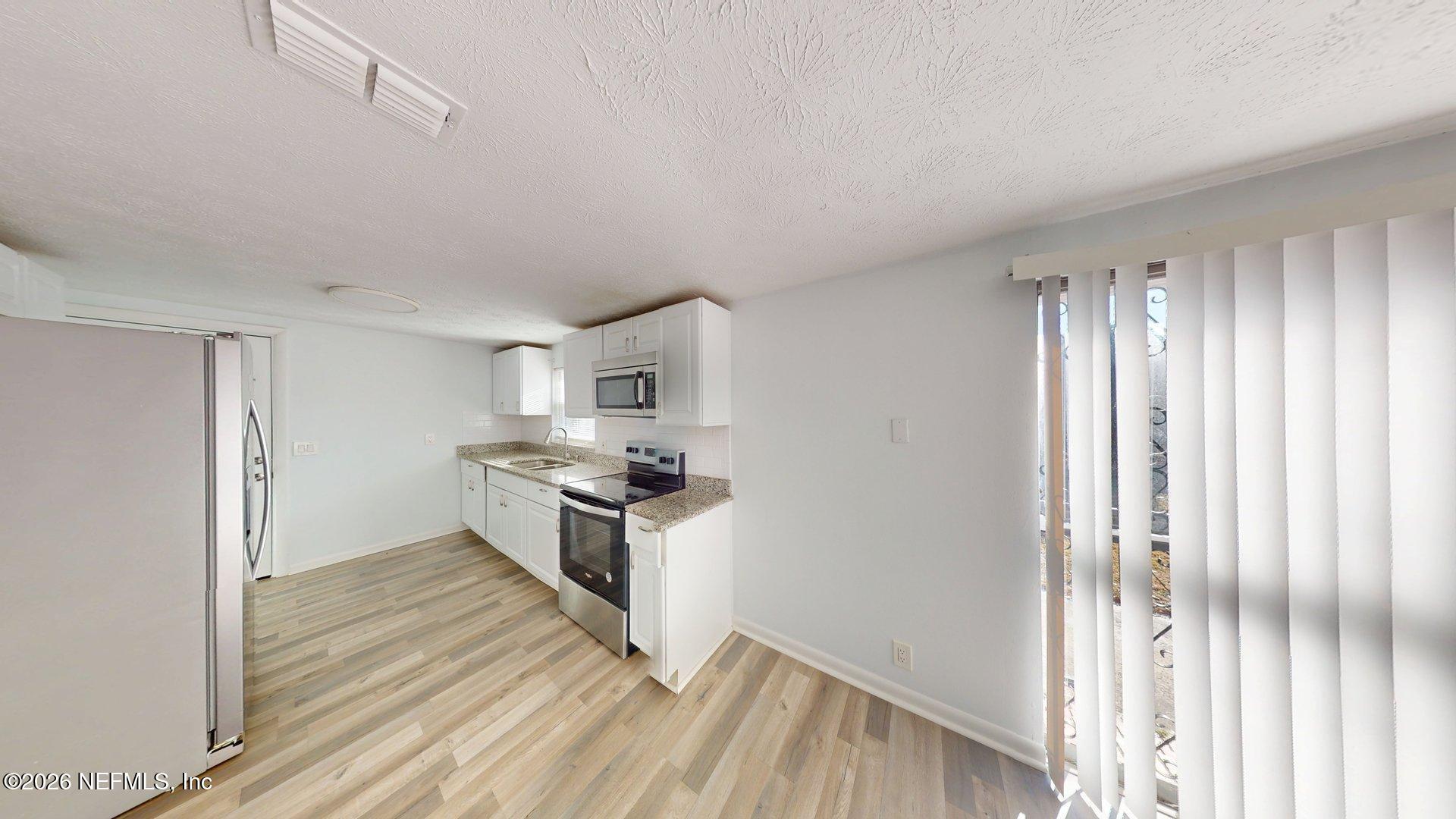 5246 Devron Drive Jacksonville, FL 32209 - Photo 6 of 18 a kitchen with stainless steel appliances a stove top oven and cabinets