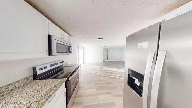 a kitchen with stainless steel appliances granite countertop a refrigerator a stove and a sink with large countertops