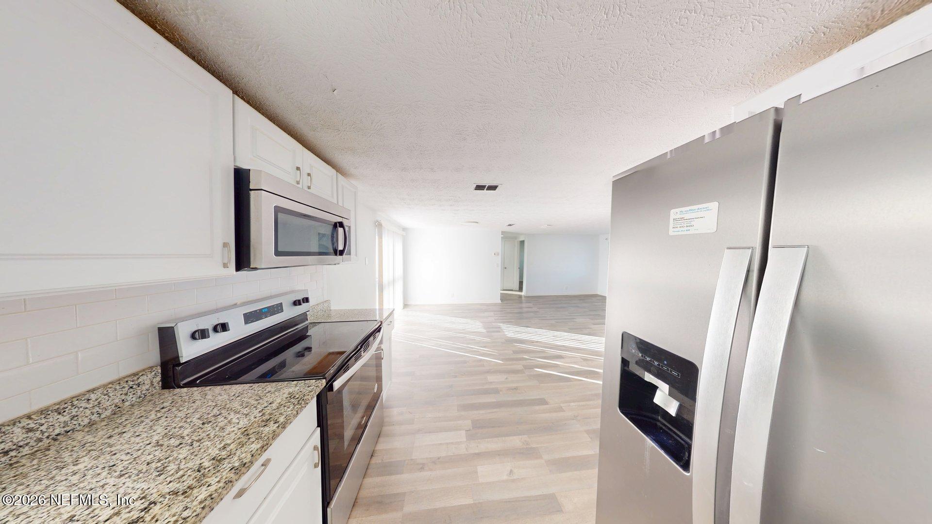 5246 Devron Drive Jacksonville, FL 32209 - Photo 7 of 18 a kitchen with stainless steel appliances granite countertop a refrigerator a stove and a sink with large countertops