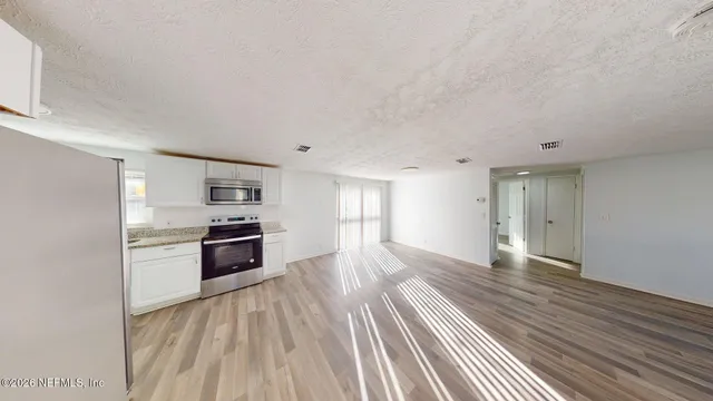 a view of a kitchen with wooden floor and electronic appliances
