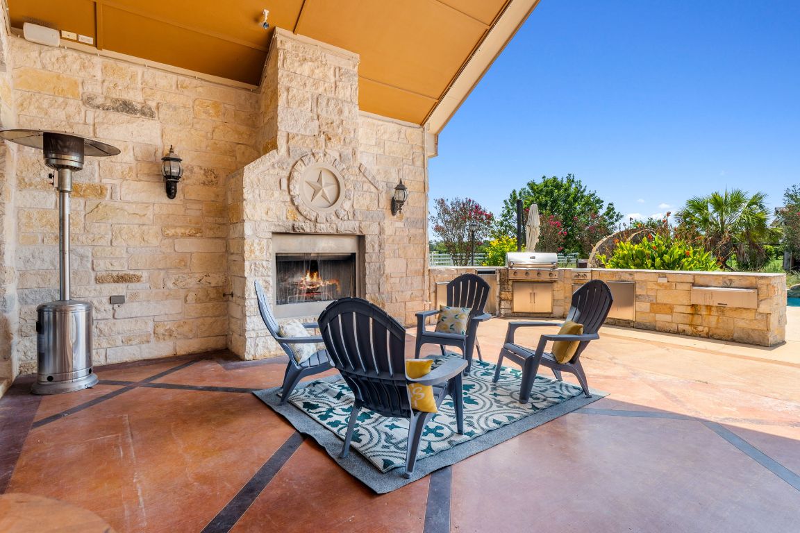 218 Courtnee's Way Georgetown, TX 78626 - Photo 15 of 36 The exterior features a beautiful stone fireplace that serves as both a focal point and a gathering spot, perfect for cool Texas evenings. Positioned to overlook the pool and outdoor kitchen, it creates a cozy, inviting atmosphere for entertaining or relaxing under the open sky ~