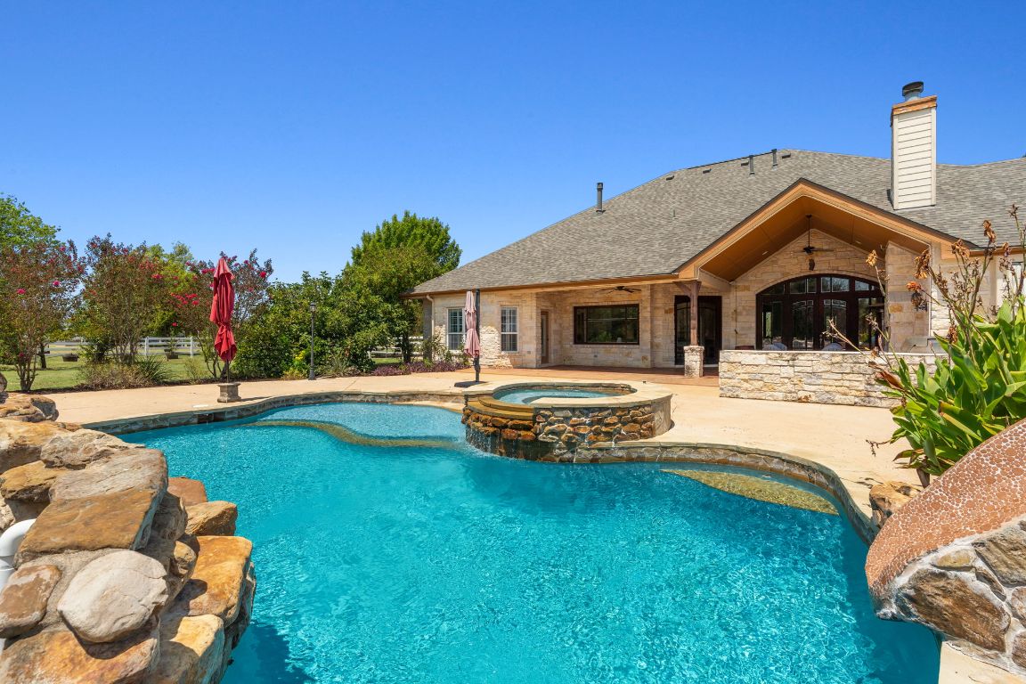 218 Courtnee's Way Georgetown, TX 78626 - Photo 16 of 36 The view showcases the sparkling pool in the foreground, inviting for both relaxation and play, with the fully equipped outdoor kitchen just beyond - complete with a grill, sink, refrigerator, warming drawer, and seating - creating the perfect backdrop for effortless entertaining and enjoying the Texas sunshine ~