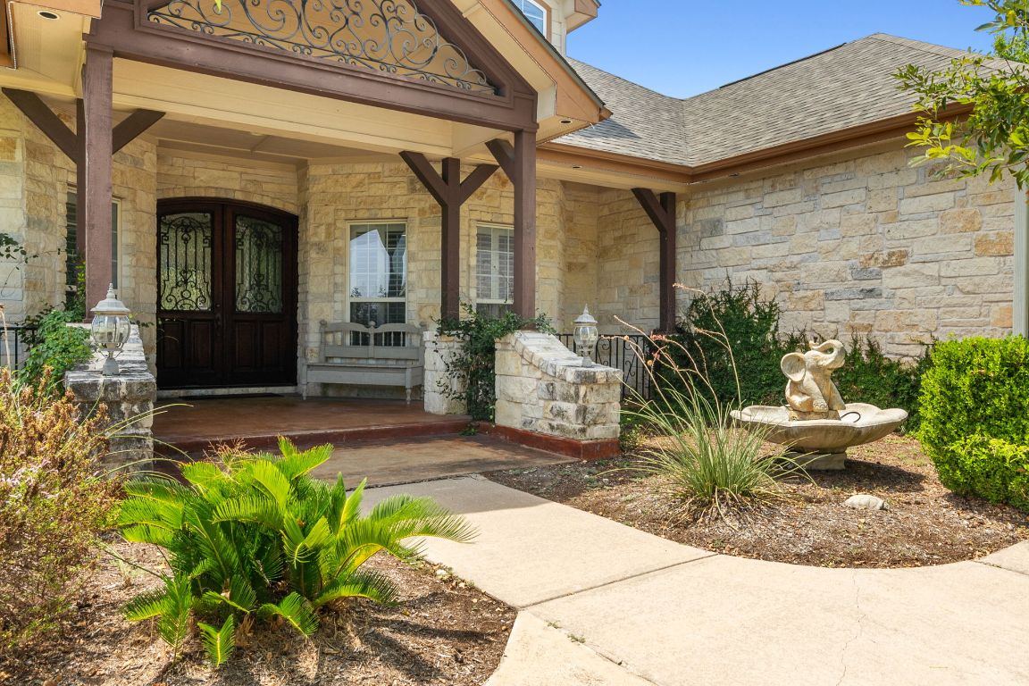 218 Courtnee's Way Georgetown, TX 78626 - Photo 4 of 36 The inviting front entry features striking wood and iron double doors that make a bold statement, opening onto a spacious porch perfect for relaxing and welcoming guests ~