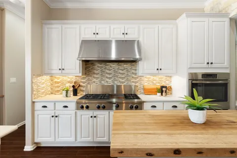 a kitchen with stainless steel appliances granite countertop a white cabinets and a stove