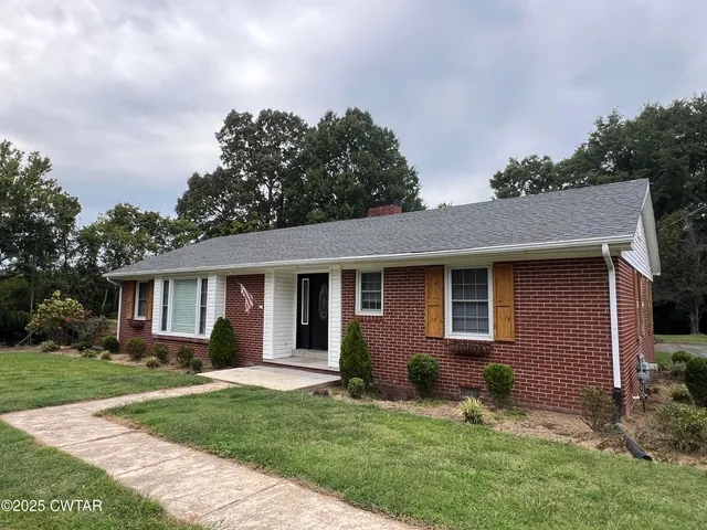 a backyard of a house with potted plants and large tree