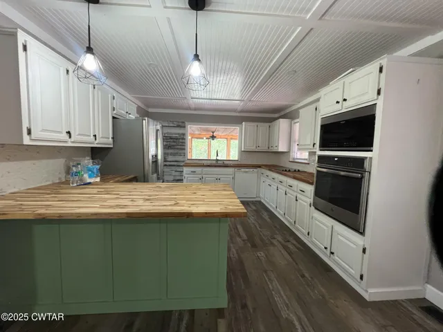 a kitchen with kitchen island granite countertop a stove a sink and dishwasher with wooden floor