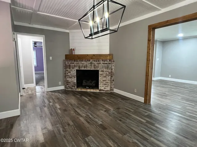 an empty room with wooden floor fireplace and staircase