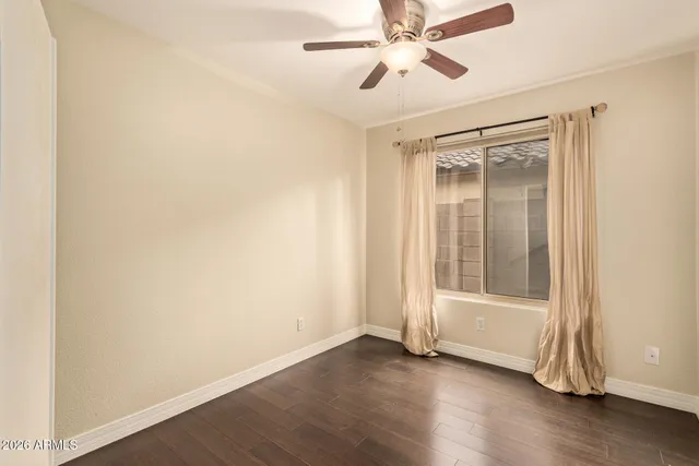 an empty room with wooden floor fan and windows